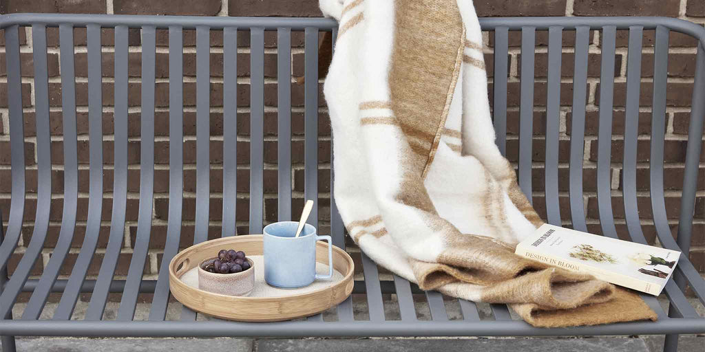 Un plaid et une tasse bleu sur un banc gris